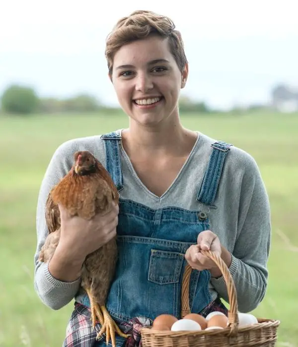 a women collecting eggs and holding her chicken on hand